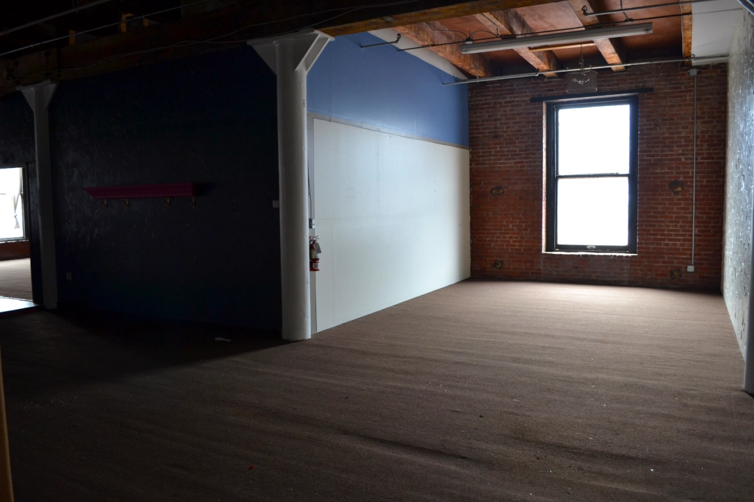 Open-concept commercial real estate space in Kansas City’s West Bottoms featuring hardwood floors, exposed ceilings, and natural light — ideal for a studio, retail shop, or creative office.