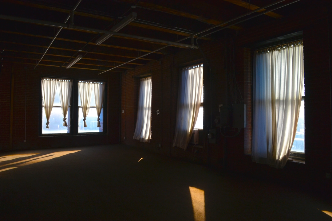 Open-concept commercial real estate space in Kansas City’s West Bottoms featuring hardwood floors, exposed ceilings, and natural light — ideal for a studio, retail shop, or creative office.