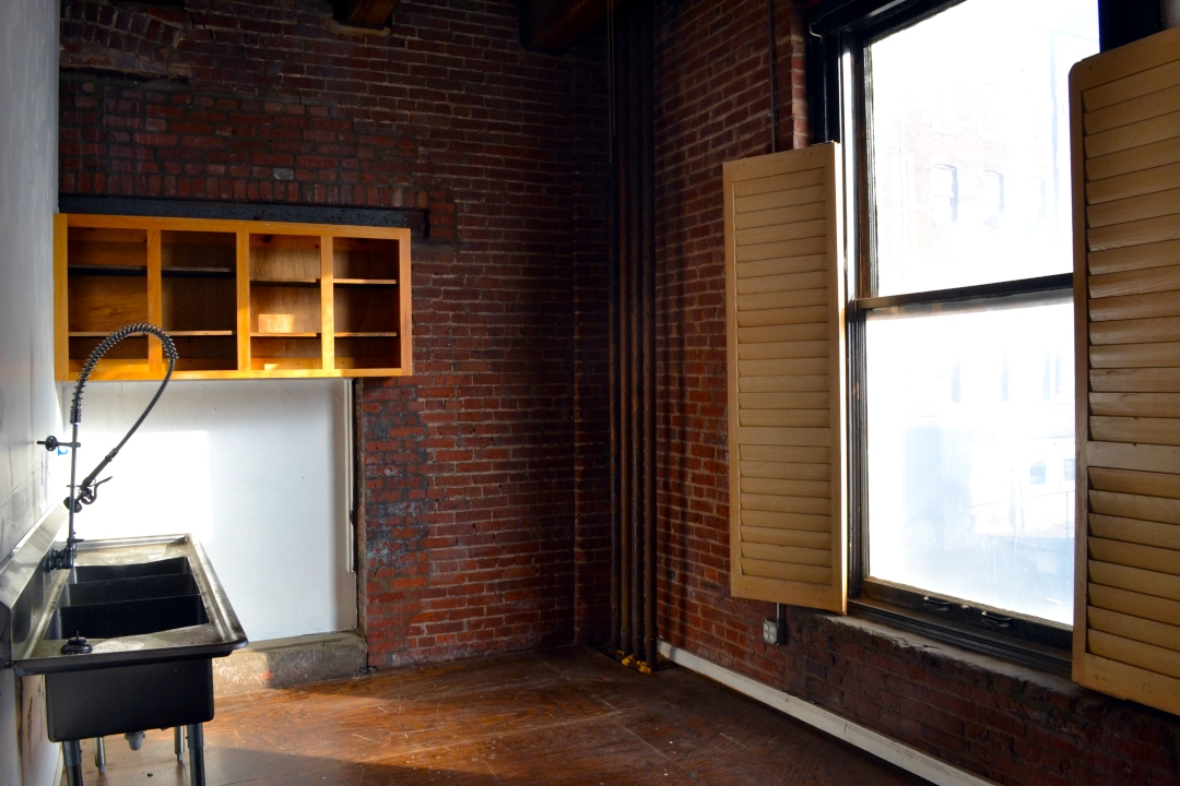 Open-concept commercial real estate space in Kansas City’s West Bottoms featuring hardwood floors, exposed ceilings, and natural light — ideal for a studio, retail shop, or creative office.