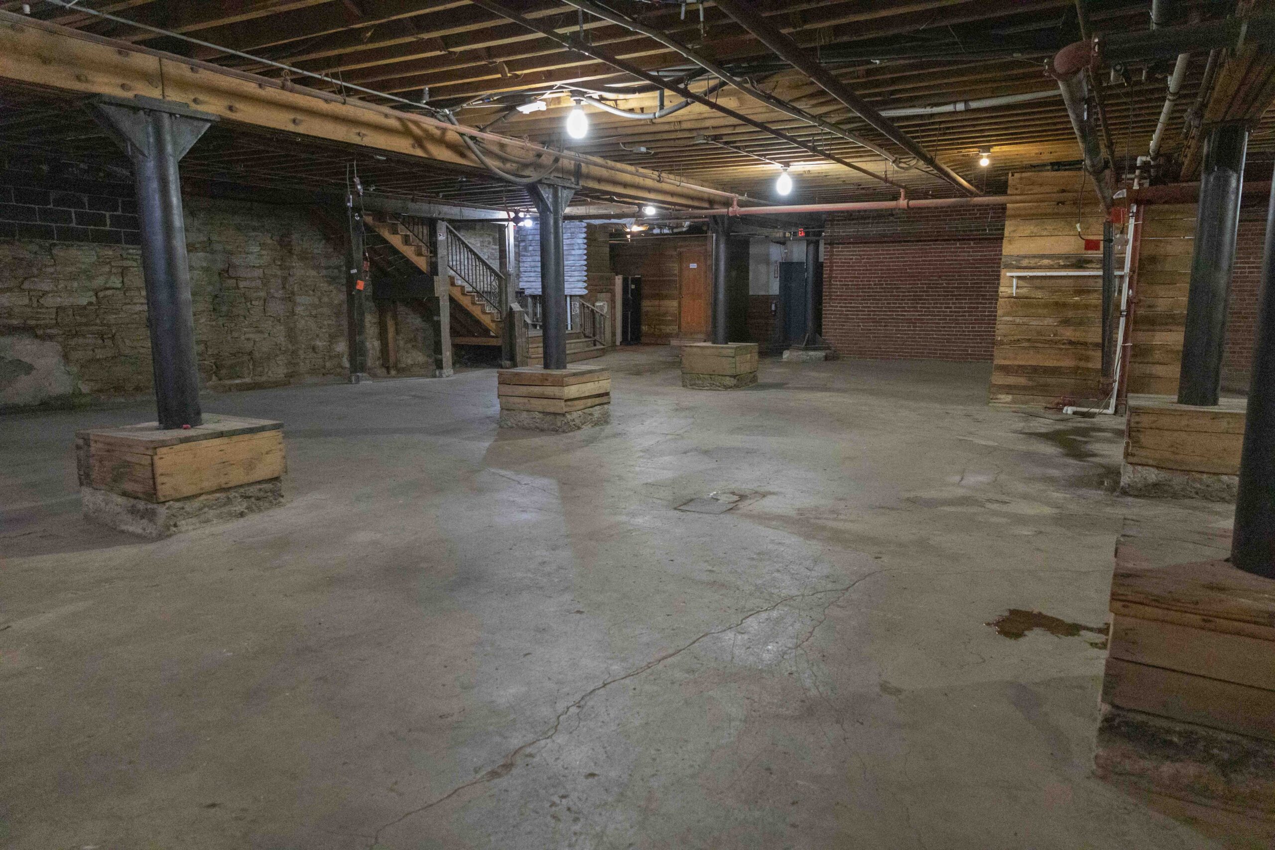 Commercial Real Estate in Kansas City's West Bottoms. Historic basement commercial space in Kansas City's West Bottoms featuring exposed brick walls, concrete flooring, steel support columns, and original industrial architecture.