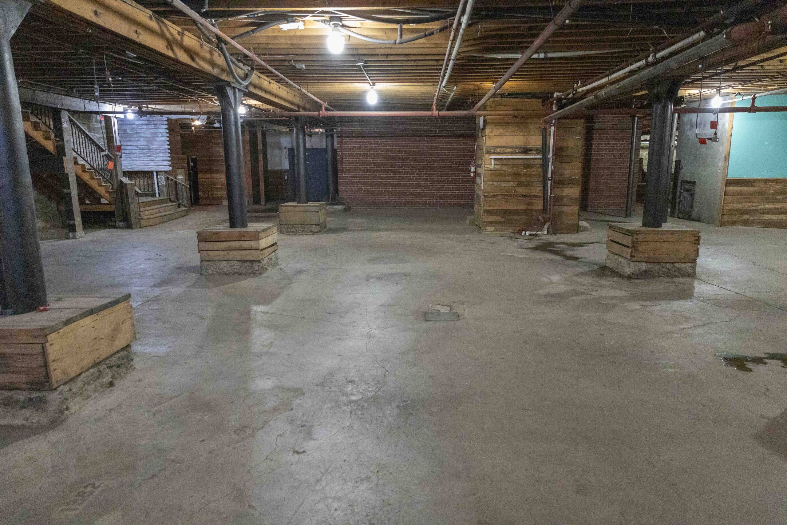 Commercial Real Estate in Kansas City's West Bottoms. Historic basement commercial space in Kansas City's West Bottoms featuring exposed brick walls, concrete flooring, steel support columns, and original industrial architecture.