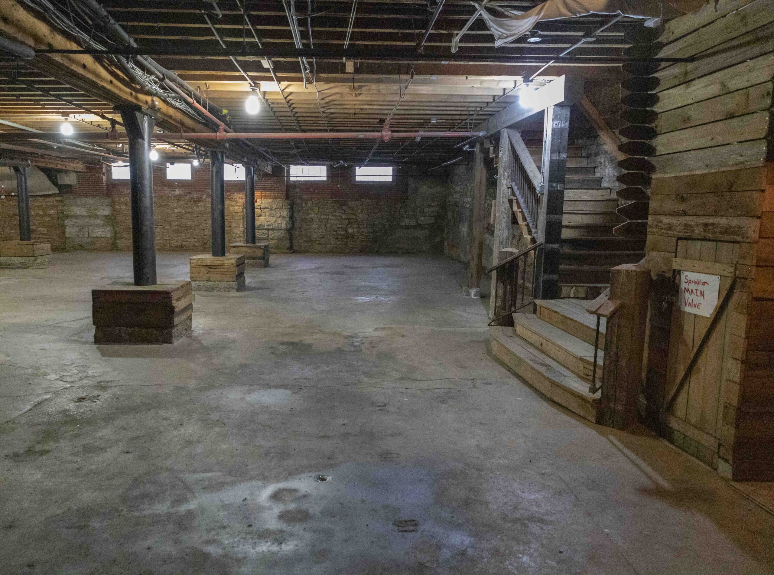 Commercial Real Estate in Kansas City's West Bottoms. Historic basement commercial space in Kansas City's West Bottoms featuring exposed brick walls, concrete flooring, steel support columns, and original industrial architecture.