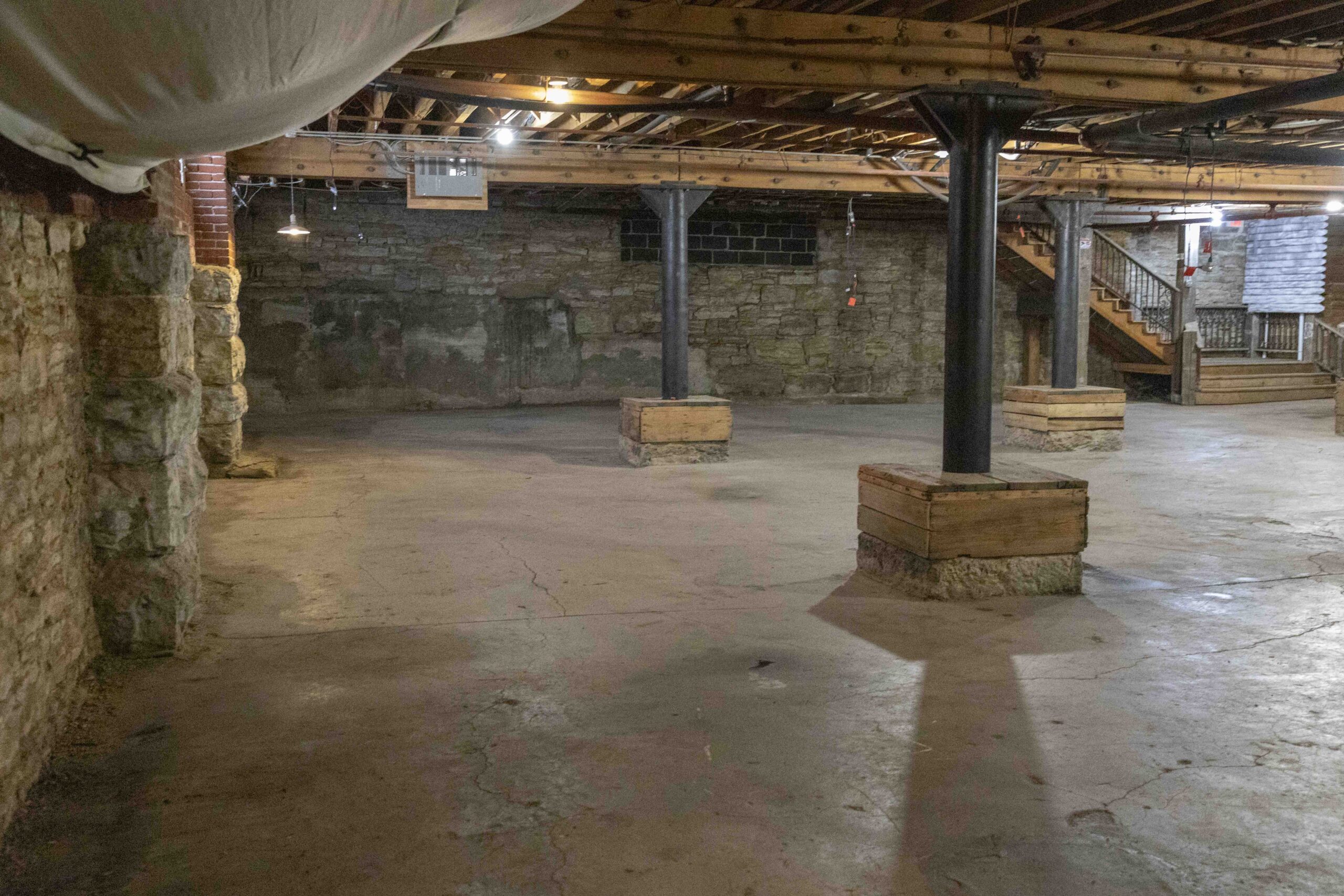 Commercial Real Estate in Kansas City's West Bottoms. Historic basement commercial space in Kansas City's West Bottoms featuring exposed brick walls, concrete flooring, steel support columns, and original industrial architecture.